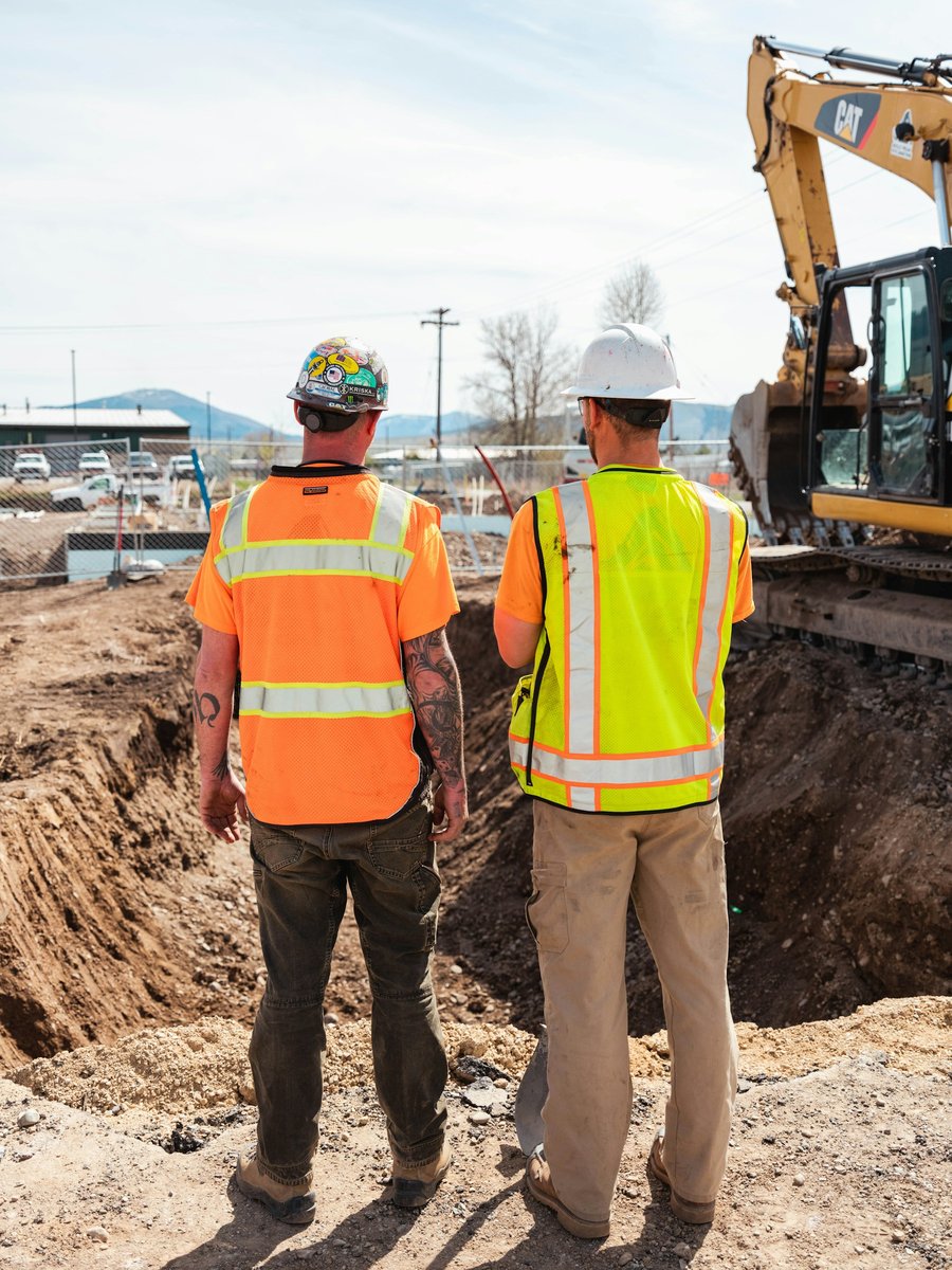 Deux ouvriers de chantier de dos, casques et gilets de sécurité